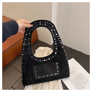 Close-up of black suede tote bag featuring silver studs and a rectangular front pocket