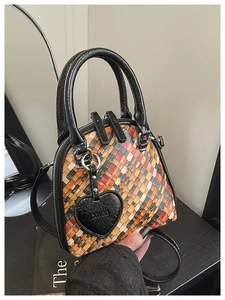 Détail du sac tressé coloré avec poignées rondes et accessoire charm en forme de cœur