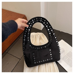 Detail of black suede tote bag featuring silver studs and an integrated oval handle