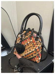 Détail du sac coquillage tissé coloré avec poignées en cuir et pendentif coeur