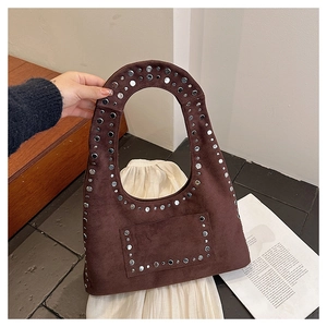 Close-up of brown suede shoulder bag featuring silver metal rivets and rounded silhouette