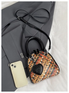 Détail du sac tressé multicolore avec bandoulière noire et charm en forme de cœur