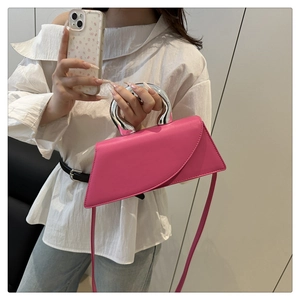Detail of fuchsia geometric handbag with silver metal handle and matching shoulder strap