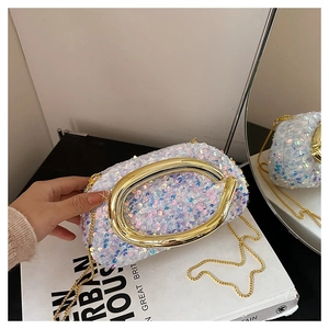 Détail d'une pochette à paillettes irisées avec boucle C dorée posée sur un livre