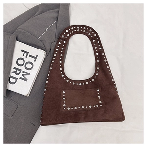 Detail of brown faux suede tote bag with silver studs on a white fabric surface