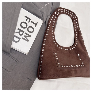Close-up of brown suede moon bag featuring silver studs on a stylish blazer background