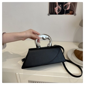 Detail of black trapezoid leather handbag with sculptural silver metal ring handle