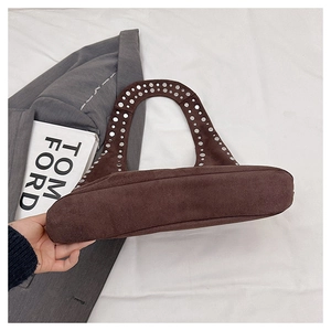 Detail view of large dark brown suede tote bag with silver studs on shoulder strap