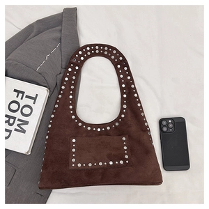 Detail of silver rivets on a coffee brown suede tote bag in a fashion-style layout