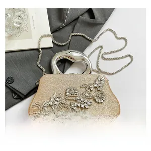 Detail of gold glitter evening bag with rhinestone floral clusters and unique metal handle