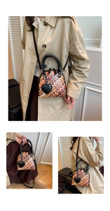 Détail d'un mini sac à main en cuir tressé multicolore avec breloque cœur et anses noires