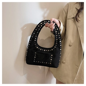 Detail of black suede tote bag with silver studs and decorative pocket on trench coat background