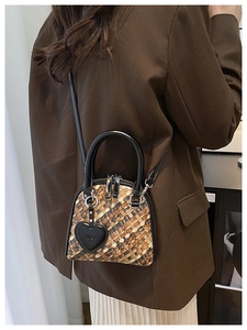 Détail du sac coquille tissé multicolore avec poignées noires et pendentif coeur