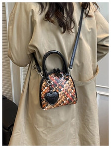Détail d'un mini sac tissé coloré avec un pendentif en forme de cœur noir et une poignée
