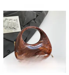 Macro detail of amber marble texture acrylic bag with golden metal chain strap