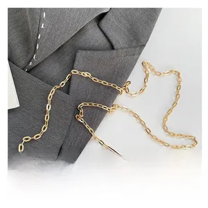 Detail of the golden metal chain strap and amber-textured acrylic handle on the handbag
