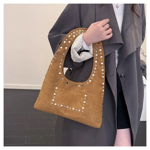 Detail of brown suede tote bag with silver metal rivets worn with a gray coat