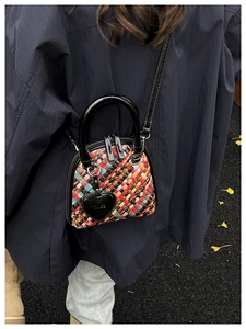 Détail d'un mini sac coquillage en cuir tressé coloré avec anses vernies noires et breloque