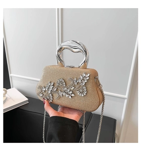 Close-up of champagne gold dinner clutch with rhinestone floral detail and metal handle