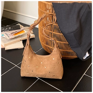 Detail of tan suede shoulder bag with gold studs, quilted pattern and bow strap design