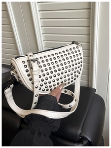 Detailed close-up of white crescent bag with silver stud rivets and top zipper closure