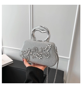 Macro shot of silver clutch bag featuring rhinestone leaf decor and metal handle