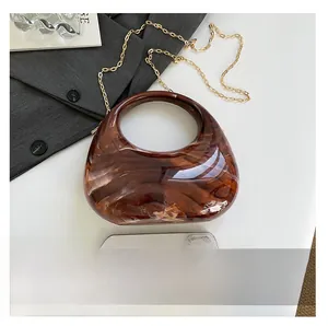 Brown marble acrylic crescent bag with gold chain strap shown next to phone for size