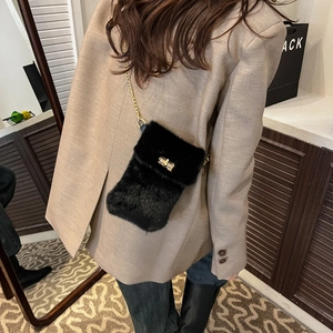 Chic black plush crossbody bag with gold chain strap and turn-lock closure on model