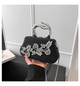 Detail of elegant black velvet evening bag with silver rhinestone flower and metal handle