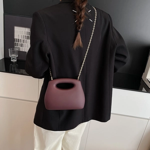 Burgundy acrylic candy-colored evening box bag with gold chain strap on model