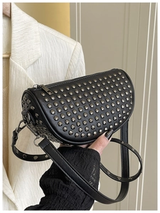 Close-up of black crossbody bag with silver rivet studs and cylinder-shaped structure