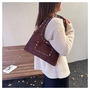 Close-up of silver rivet details on a dark brown suede shoulder bag with a vintage feel
