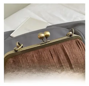 Détail du fermoir en métal bronze vintage et des crochets sur un sac à franges en daim