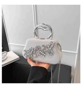 Detail of white glitter evening bag with crystal flower ornament and silver metal handle