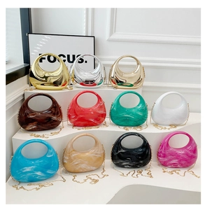 Multiple colorful acrylic crescent clutch bags with gold metal chains on display