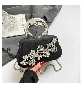 Close-up of black glitter evening bag with rhinestone flower and silver handle