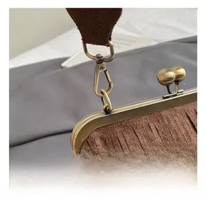 Détail du fermoir vintage en bronze et du crochet métallique sur le sac à franges brun