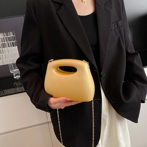 Minimalist ginger yellow acrylic box bag with gold chain strap shown on a model