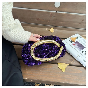 Détail des paillettes violettes scintillantes et de la poignée dorée du sac de soirée