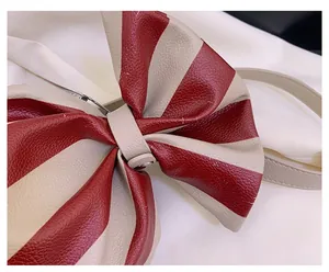 Détail du sac à nœud rayé rouge et crème montrant la texture cuir et le rivet