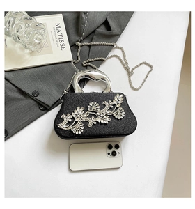 Size comparison of black rhinestone evening clutch bag next to a smartphone