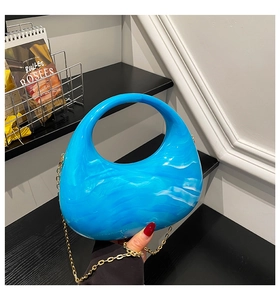 Close-up of blue marble acrylic crescent bag with golden chain and water ripple texture