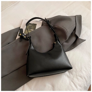 Detail of adjustable golden metal buckle on black hobo shoulder bag with smooth texture