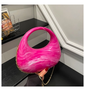 Detail shot of bright pink marble acrylic crescent bag with golden chain strap detail