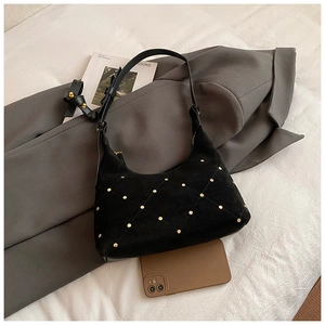 Detail of black matte suede baguette bag with golden studs and elegant diamond pattern