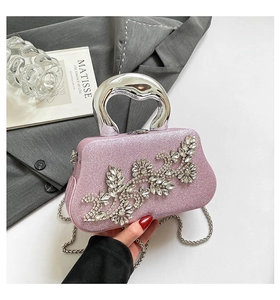 Close-up of pink glitter evening bag with rhinestone flower and silver metal handle