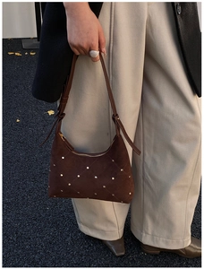 Detail of dark brown suede shoulder bag with golden studs in a diamond pattern