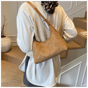 Detailed close-up of brown suede hobo bag featuring gold studs and quilted stitching