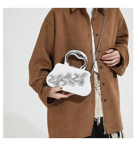 Close-up of white evening bag with rhinestone floral patterns and silver metal handle