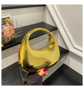Detail of creative crescent metal handbag in mirror gold finish with a sleek chain strap